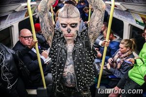 Фото тату: Мужчина с татуировкой в виде черепа на лице, в метро. Черно-белый стиль, провокационный образ, татуировки на теле.